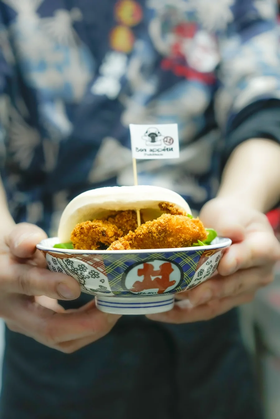 Un donburi au poulet croustillant tenu à deux mains